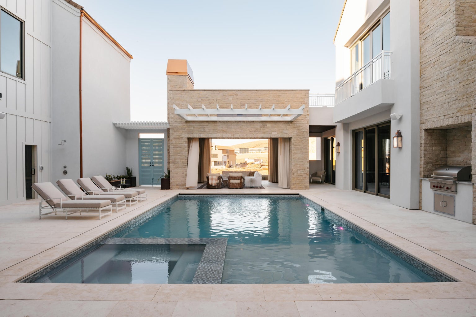 Resort-style pool area featuring a rectangular pool, integrated spa, and expansive paved decking