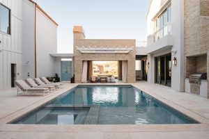 Resort-style pool area featuring a rectangular pool, integrated spa, and expansive paved decking