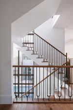 Multilevel staircase featuring black metal balusters with unique u-shaped elements and light wood handrails