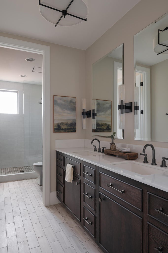 Dual vanity with dark wood cabinetry, white countertops, and matte black hardware