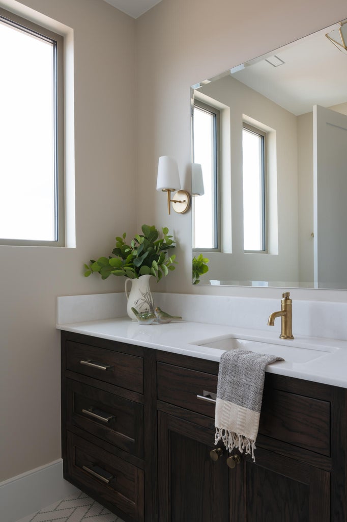 Bathroom vanity featuring dark wood-finish cabinetry with silver-tone hardware, a white countertop, and an undermount sink