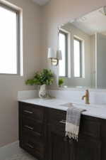 Bathroom vanity featuring dark wood-finish cabinetry with silver-tone hardware, a white countertop, and an undermount sink
