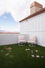 Rooftop deck featuring artificial turf, a low privacy wall, and two outdoor swivel chairs