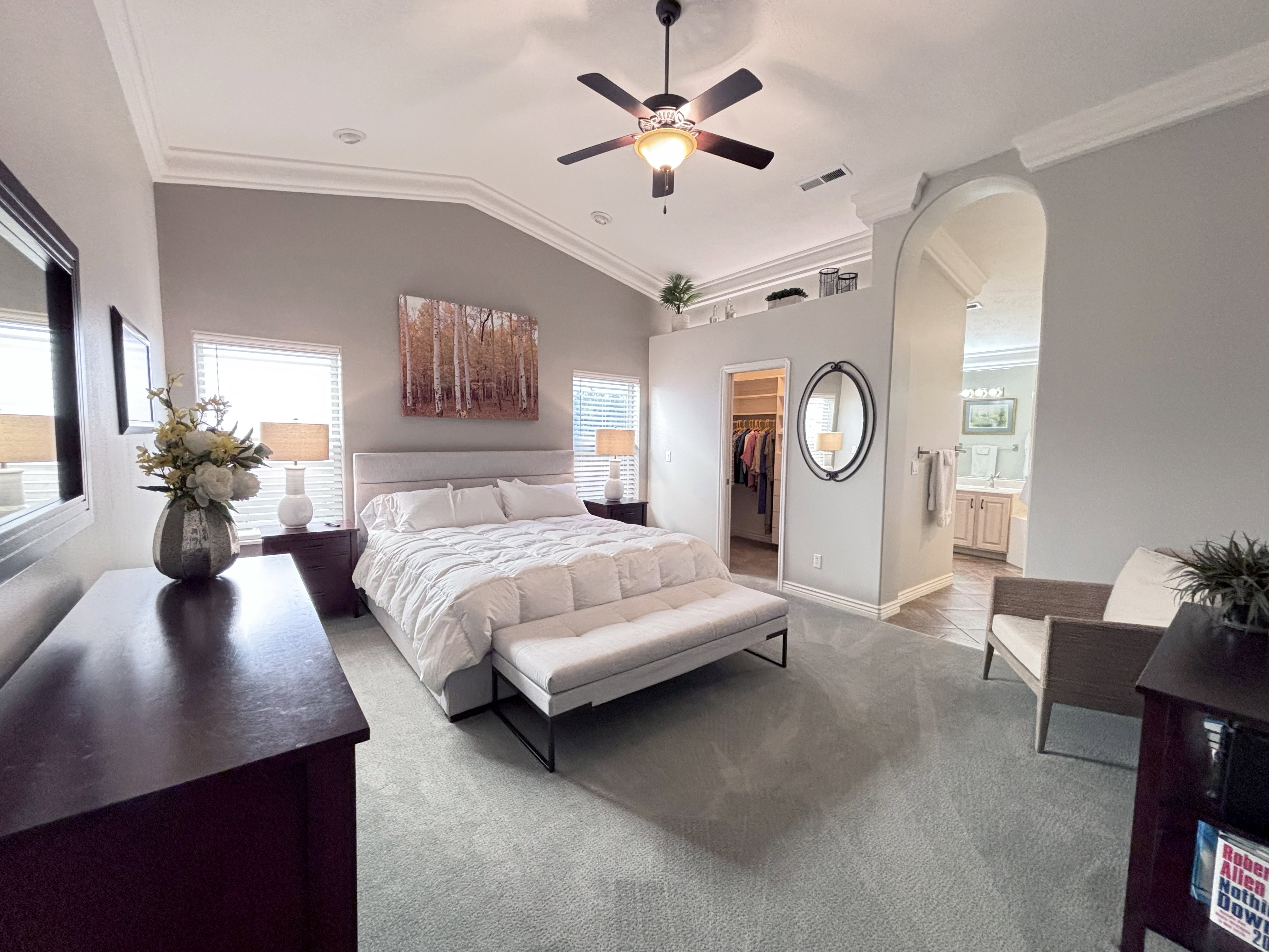 Spacious room featuring vaulted ceilings with crown molding, a ceiling fan, and carpeted flooring
