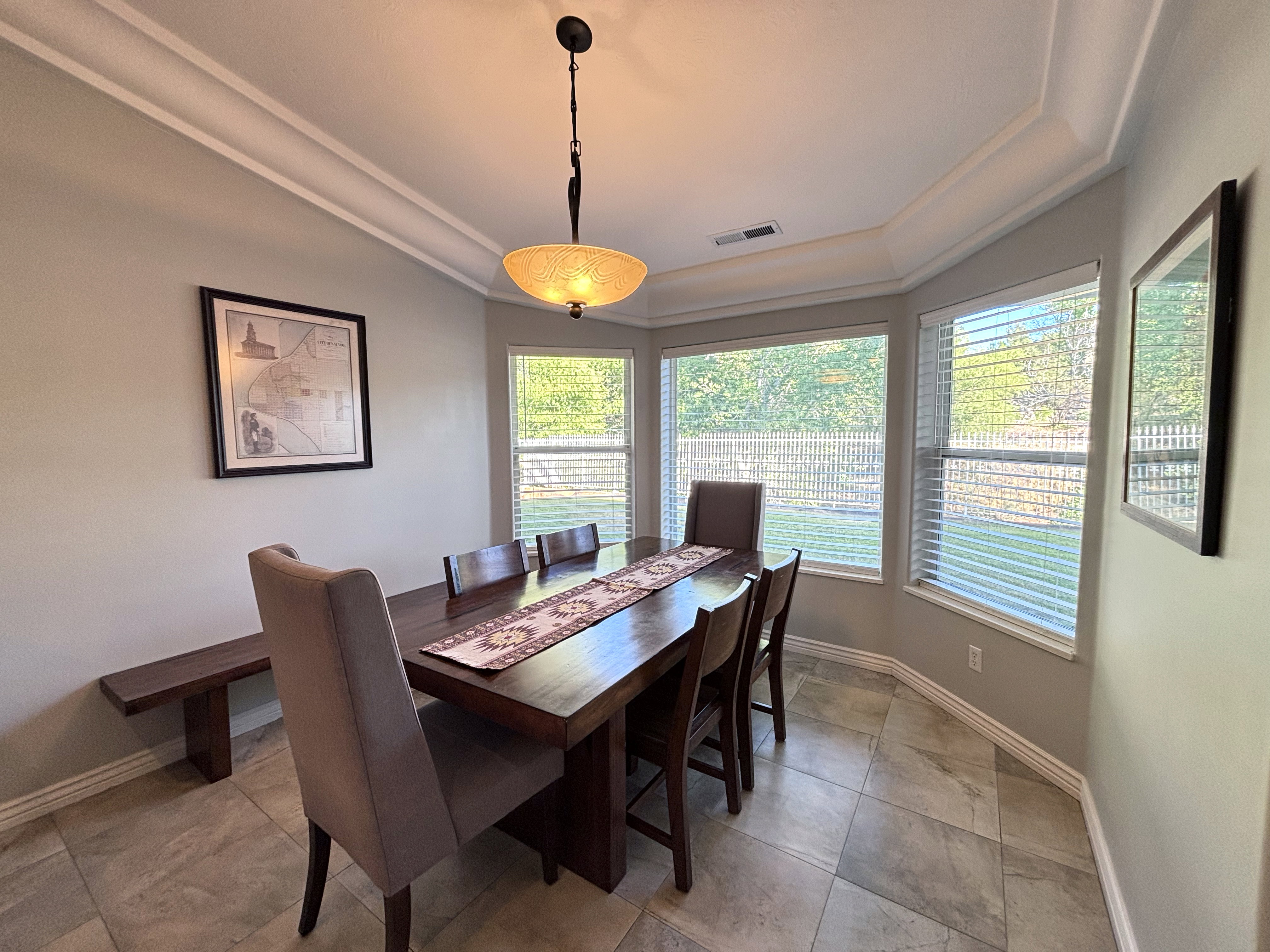 Dining area featuring a bay window, crown molding, a central chandelier, and tile flooring