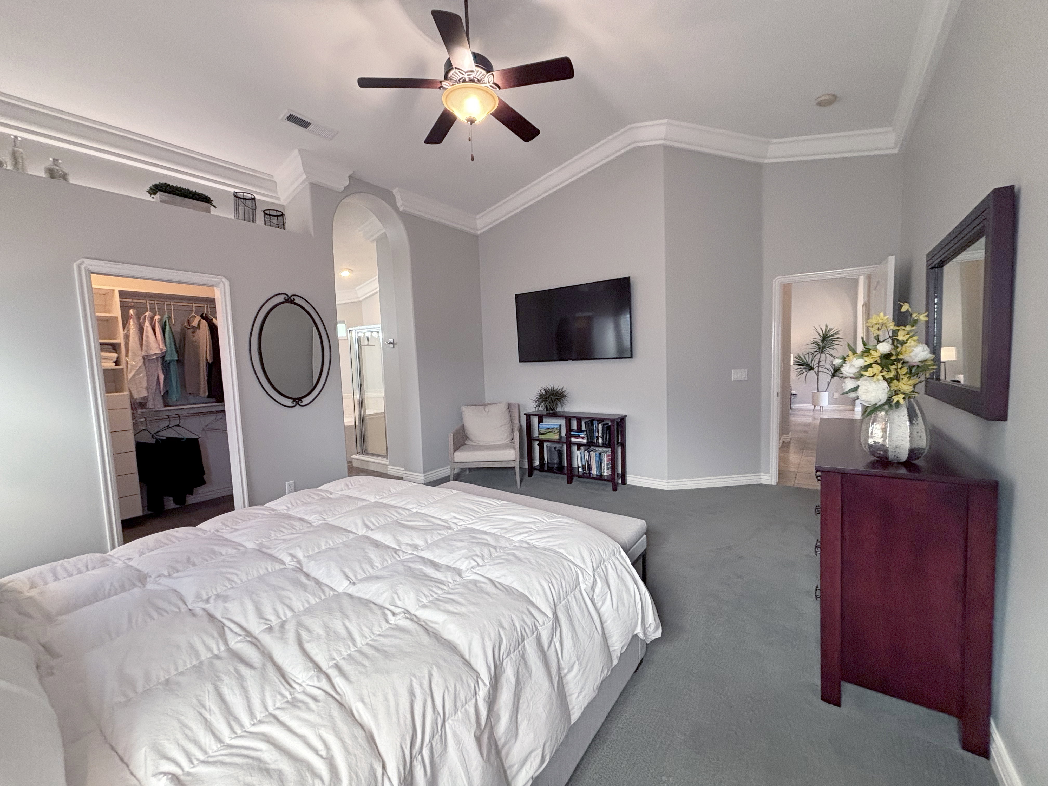 Spacious bedroom featuring vaulted ceilings with crown molding, a ceiling fan, and plush carpeting