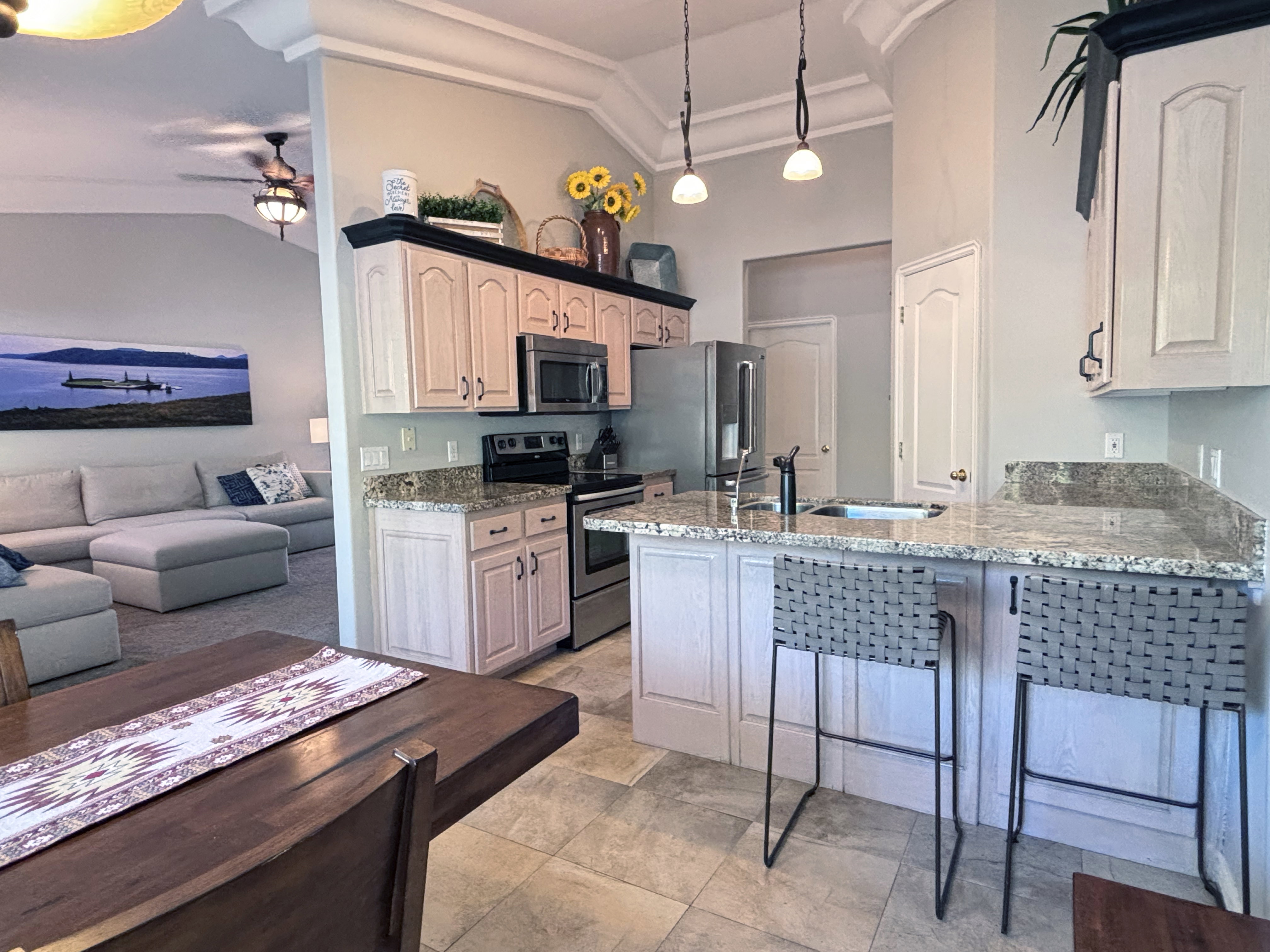 Kitchen featuring light-toned cabinetry, stainless steel appliances, granite countertops, and tile flooring