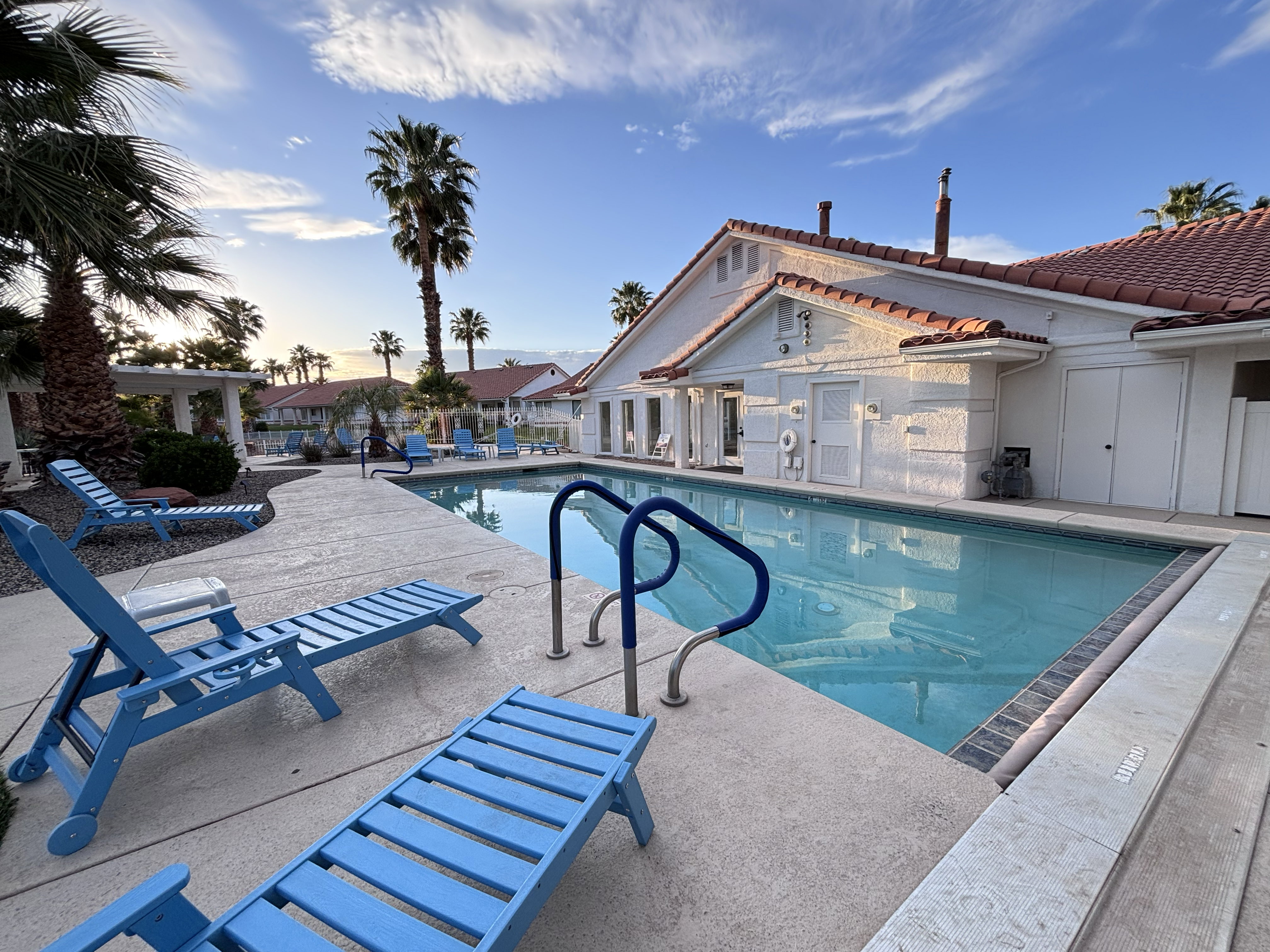 Rectangular swimming pool featuring a concrete deck surround and integrated entry handrails