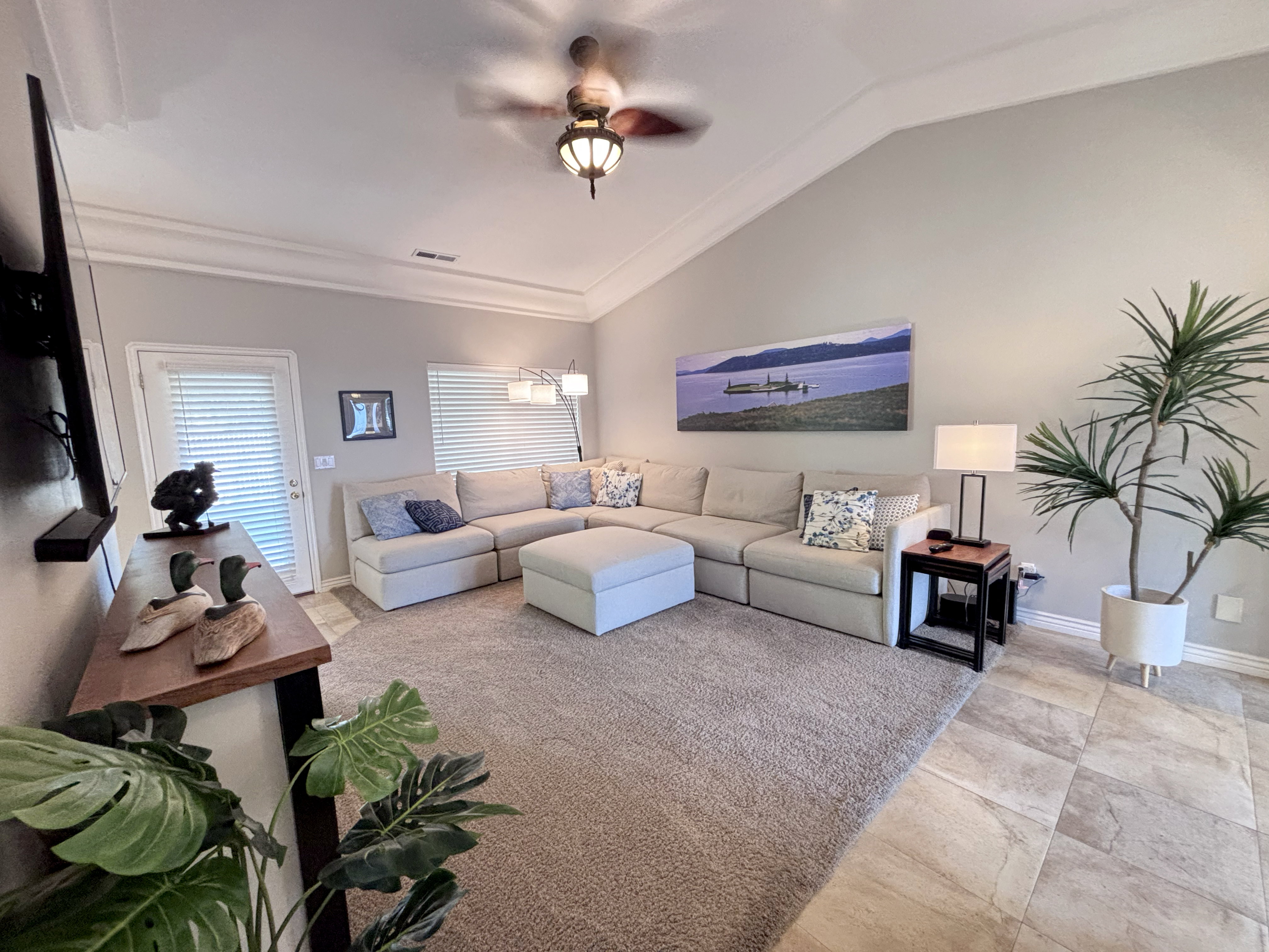 Living area featuring a vaulted ceiling with crown molding and a ceiling fan