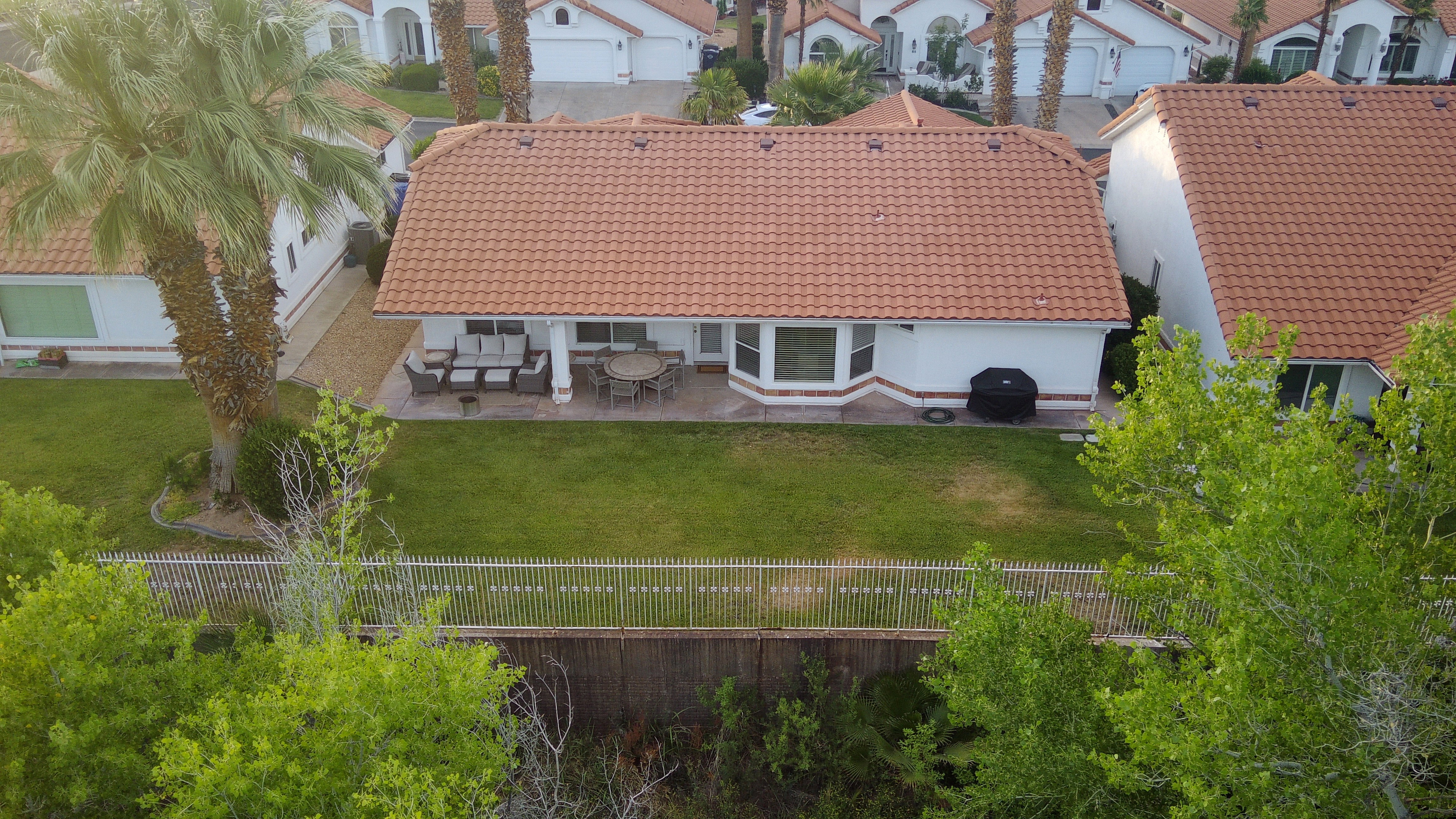 Rear exterior featuring a red tile roof, covered patio, bay window, and a white fence