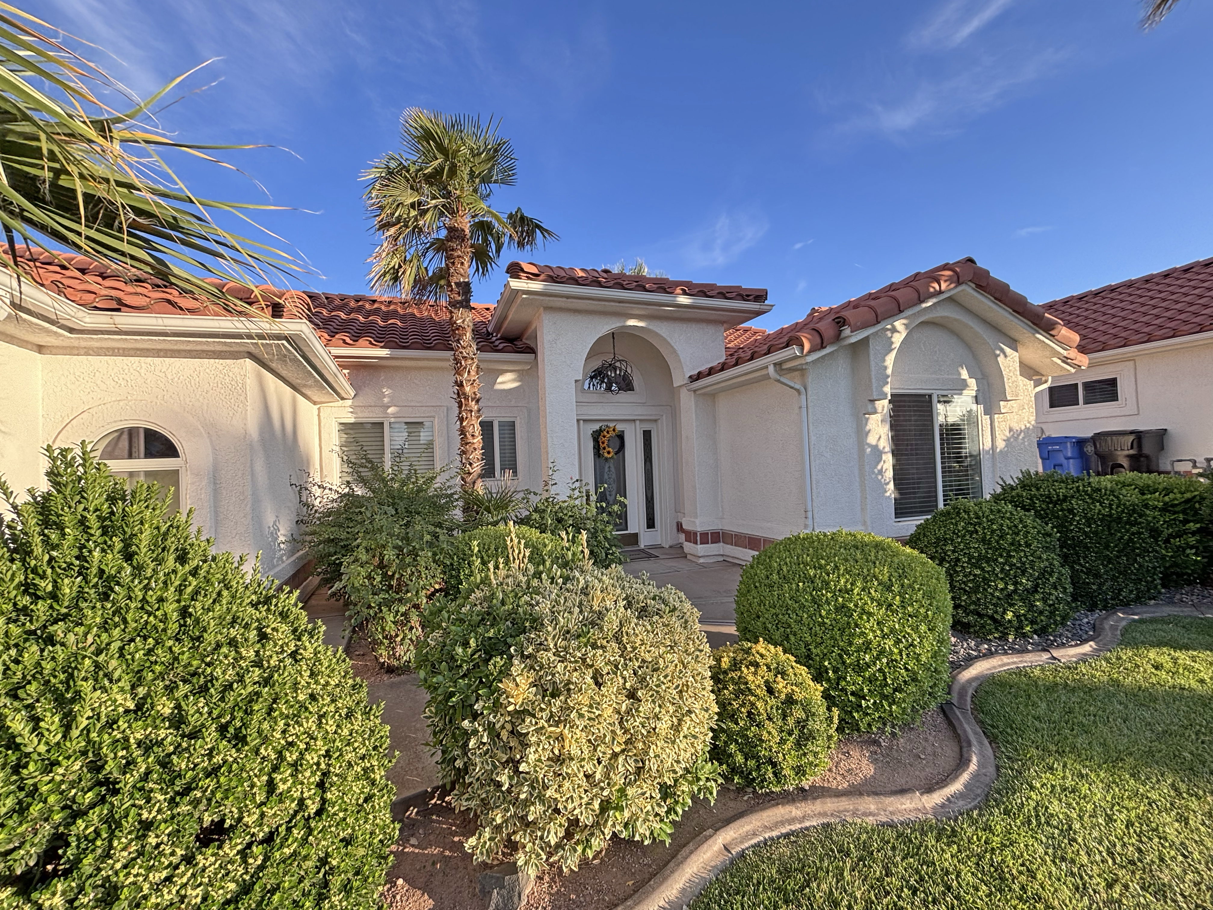 Stucco exterior with a terracotta tile roof, featuring a prominent palm tree