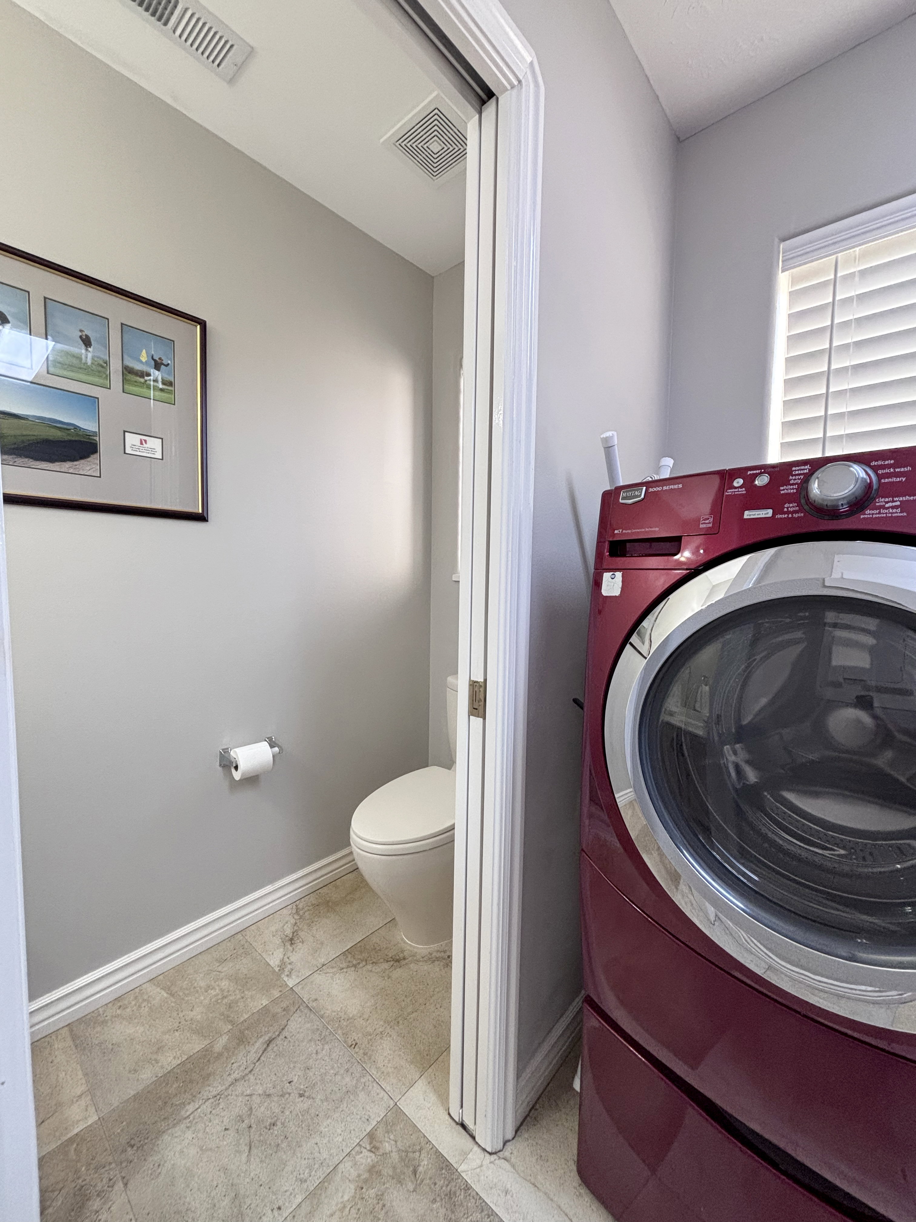 Laundry area featuring tile flooring, neutral wall paint, and a window with horizontal blinds