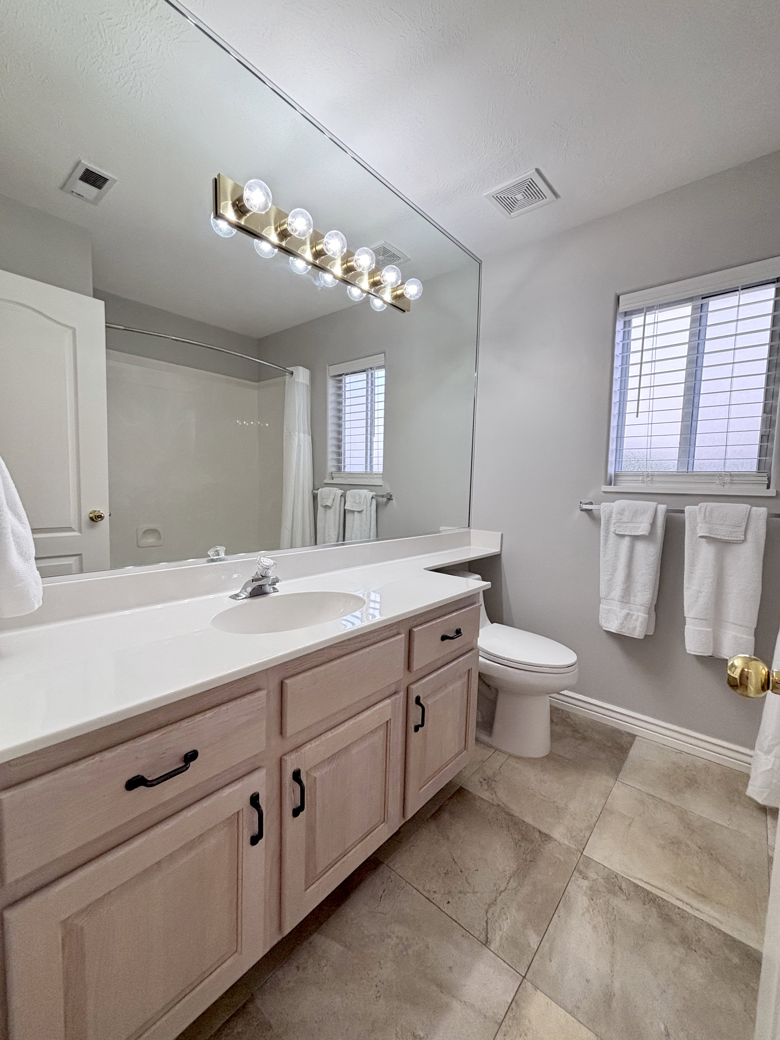 Bathroom featuring a large vanity with an integrated sink, light-colored cabinetry, and a full-width mirror
