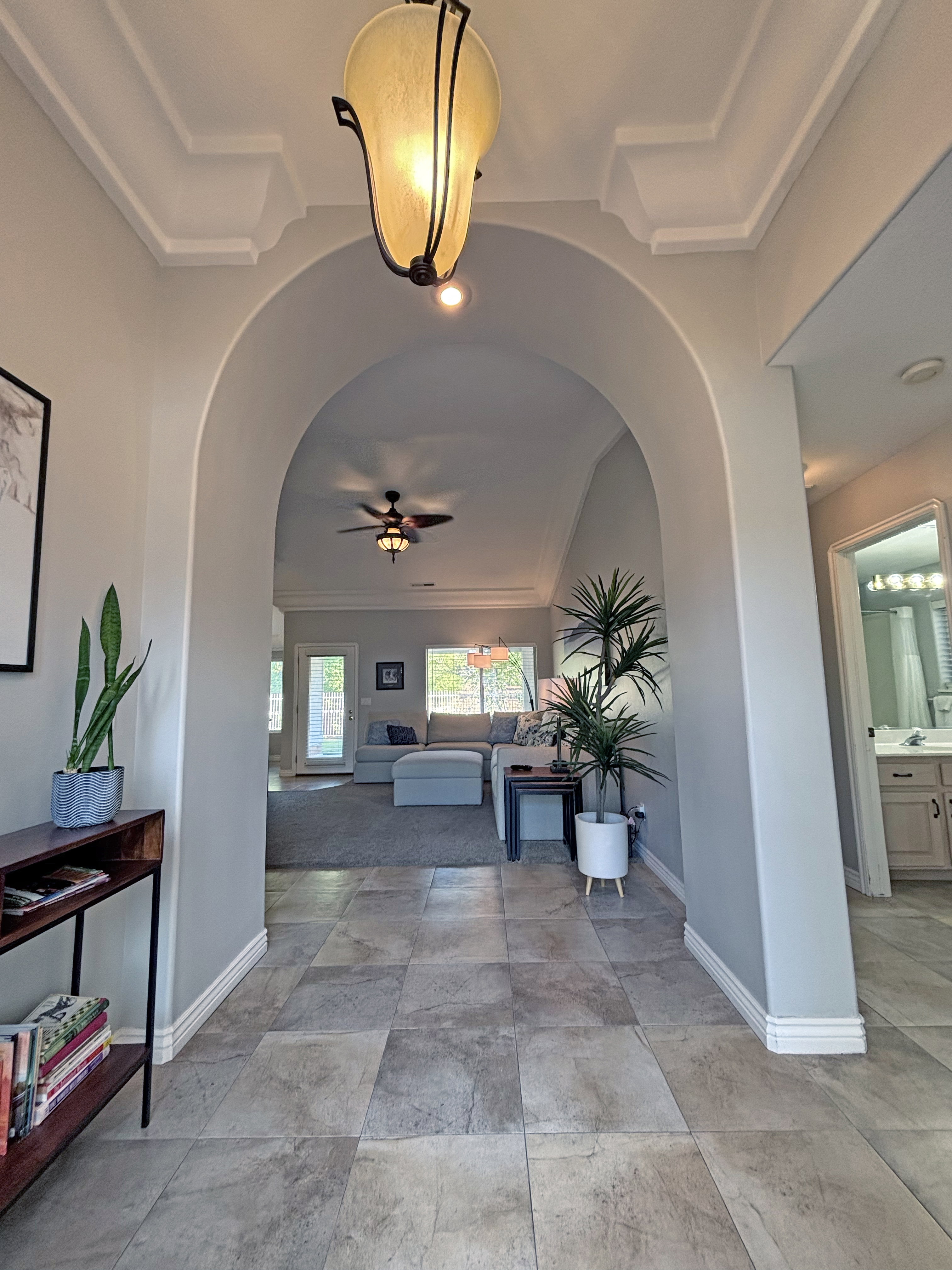 Archway entrance featuring square tile flooring and decorative crown molding