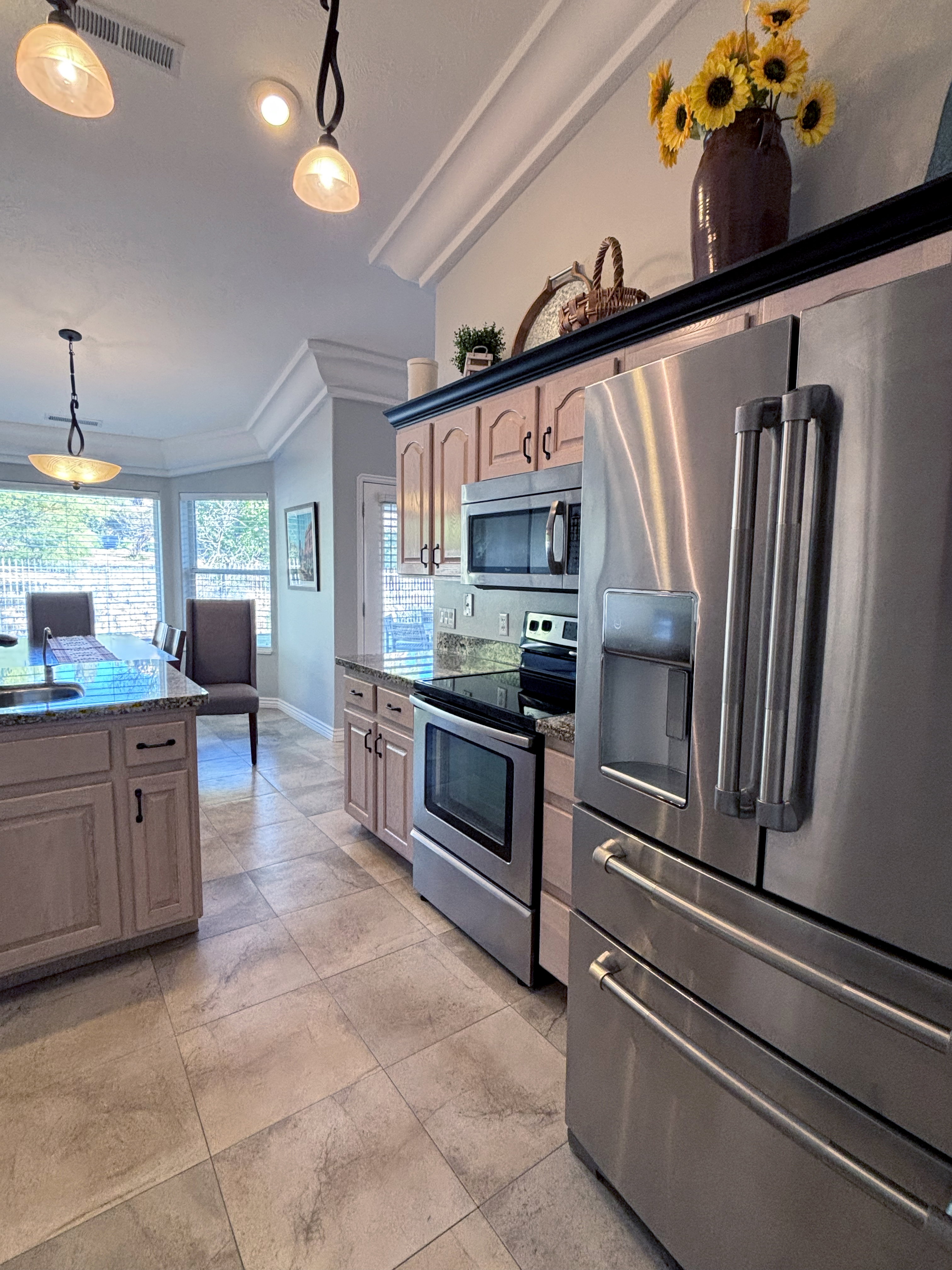 Modern kitchen featuring stainless steel appliances, neutral tile flooring, light-toned cabinetry, granite countertops, and recessed lighting