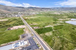 Expansive open land with a paved road, mountainous backdrop, a commercial building featuring rooftop solar panels, and a visible body of water