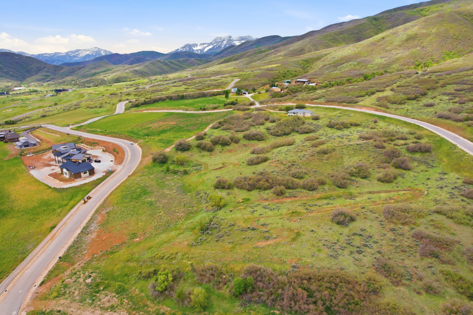 Expansive mountain landscape featuring varied terrain with verdant hillsides and distant snow-capped peaks