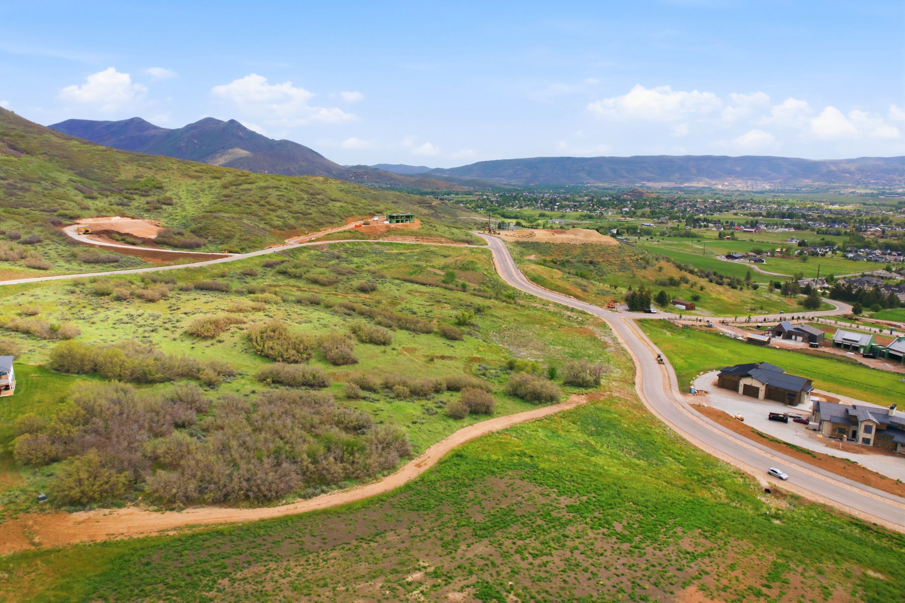 Expansive undeveloped land featuring rolling green hills and distant mountain ranges