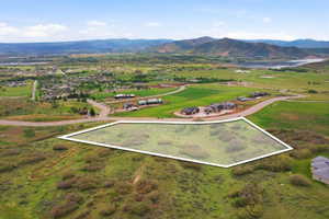 Generous land parcel featuring a gentle slope, surrounding green spaces, and distant mountain and water scenery