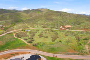 Expansive mountain landscape featuring rolling green hills and scattered brush