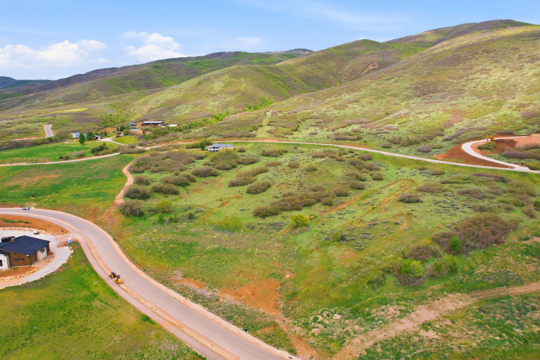 Expansive elevated terrain featuring rolling hills with natural foliage and established roadways