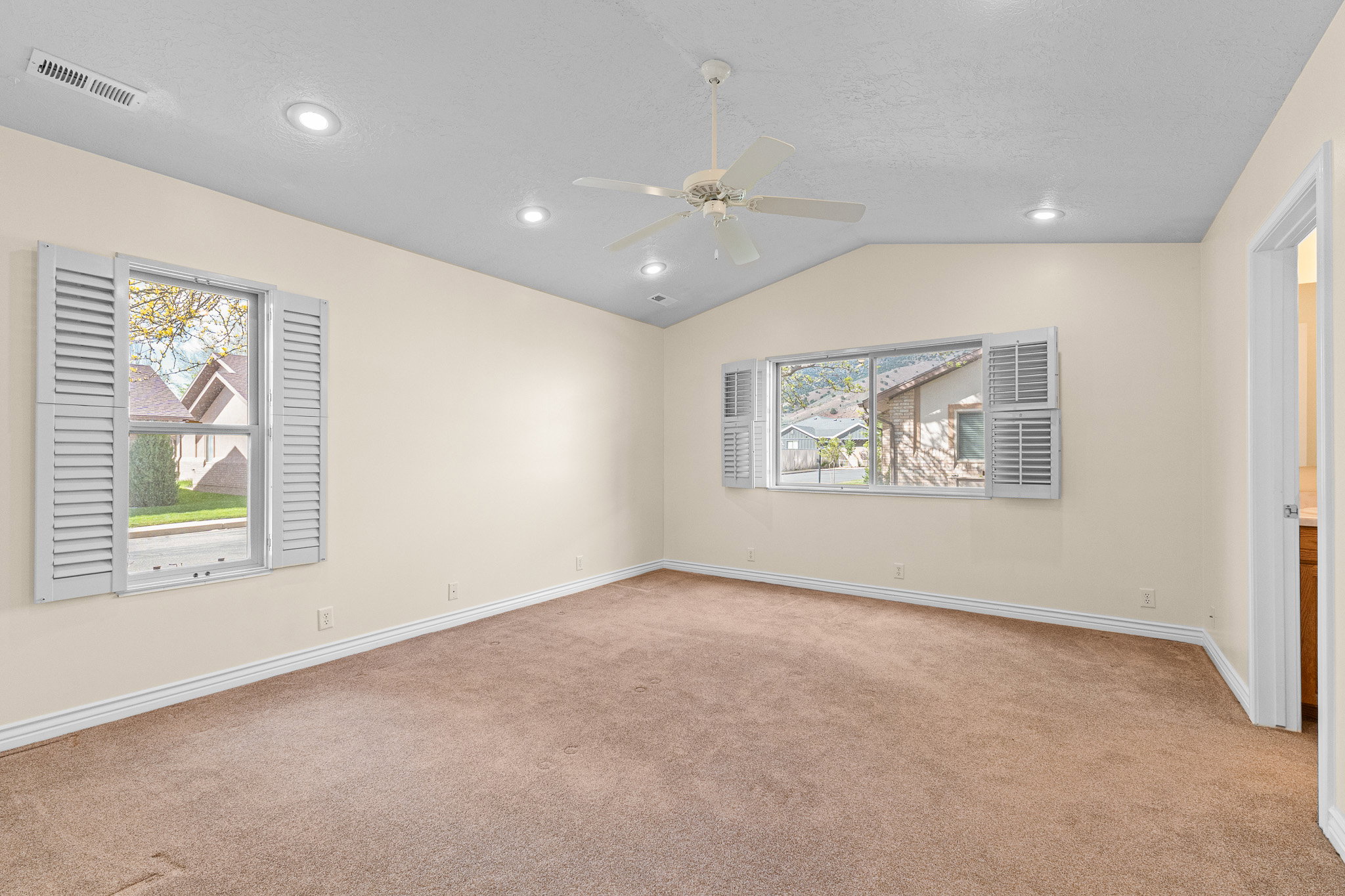 Carpeted interior space featuring vaulted ceilings and recessed lighting