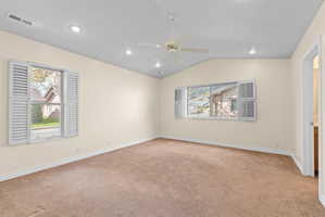 Carpeted interior space featuring vaulted ceilings and recessed lighting