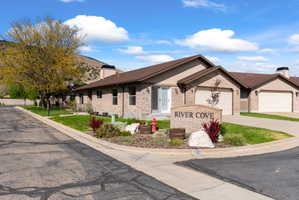 Brick facade structure featuring attached garages, a prominent community monument sign, and a manicured lawn