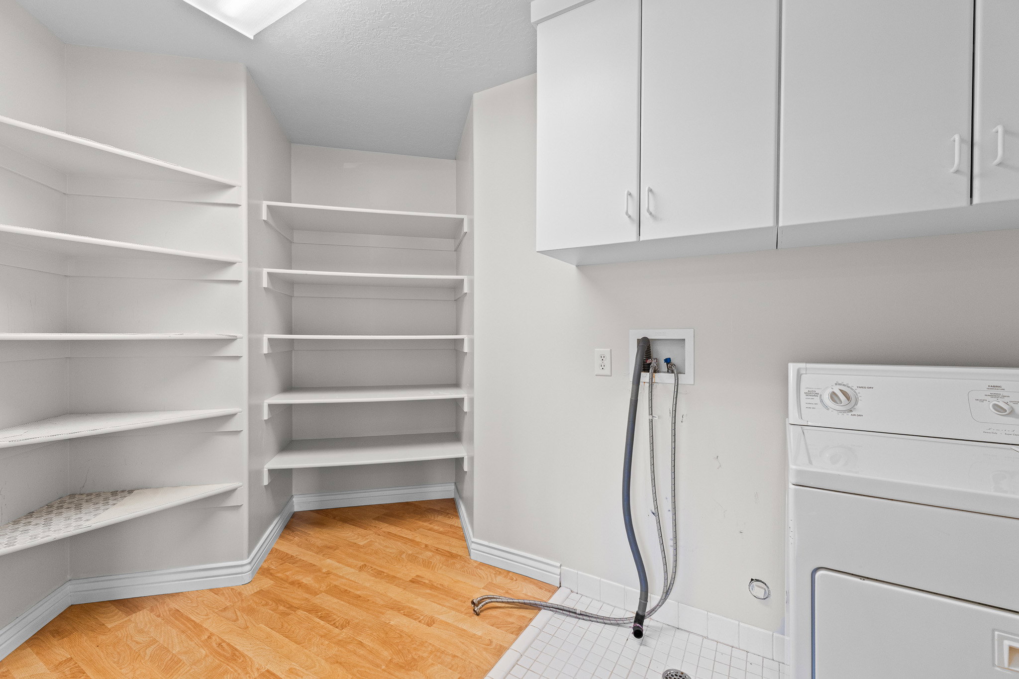 Dedicated laundry area featuring a white appliance hookup, upper cabinetry, and tile flooring