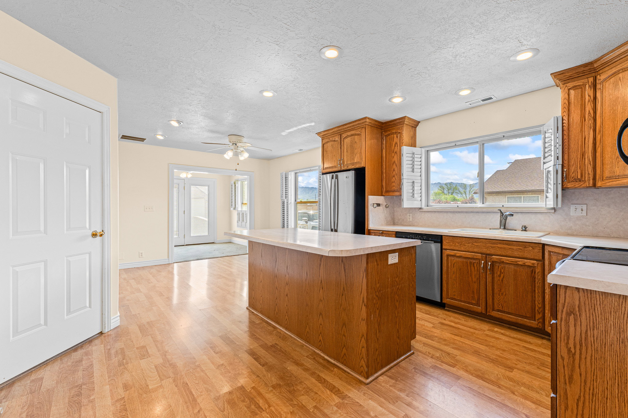 Kitchen featuring wood-finish flooring, wood cabinetry, stainless steel appliances, and a central island with a light-toned countertop