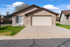 Brick and stucco exterior featuring a two-car garage with a paneled door, a concrete driveway, and a front entry with glass paneling