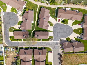 Aerial view of a residential community featuring multiple brown-roofed structures, paved driveways, and manicured green spaces