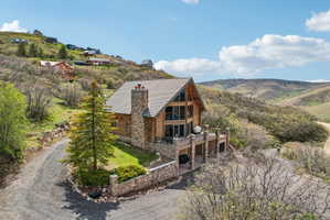 Log cabin style exterior featuring a stone chimney, extensive window-wall, and a multi-level deck
