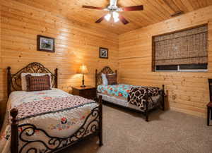 Wood-paneled room featuring a vaulted ceiling with a ceiling fan, carpeted flooring, and a window with a woven Roman shade