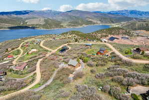 Aerial perspective of a mountainside community featuring various architectural styles, winding dirt roads, and abundant natural foliage