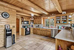 Log cabin kitchen featuring exposed ceiling beams and wood-paneled walls