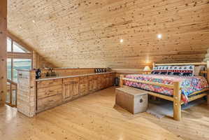 Spacious loft area featuring extensive wood-finish flooring, wood-paneled walls, and a wood-paneled sloped ceiling with recessed lighting