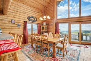 Expansive dining area featuring natural wood log walls and a vaulted ceiling