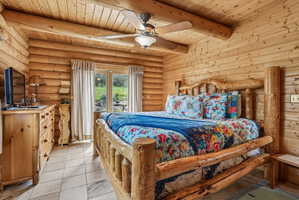 Bedroom featuring natural log walls and ceiling with exposed log beams