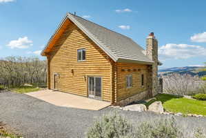 Wood-sided cabin exterior featuring a stone chimney, metal roof, and exposed wood eaves