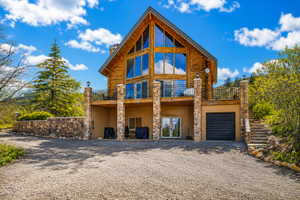 Log-style home featuring an A-frame design with expansive glass panels