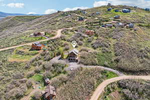 Sloping hillside property featuring a multi-level residence with extensive natural landscaping and unpaved access roads