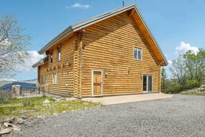 Log cabin exterior featuring a pitched roofline, exposed log construction, a solid wood entry door, and sliding glass doors
