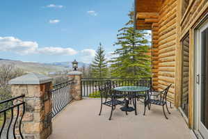 Exterior patio featuring a log cabin facade, stone pillars, wrought iron railing, and large sliding glass doors