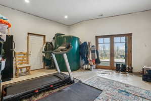 Spacious utility area featuring concrete flooring, a white paneled door, and double French doors with transom windows