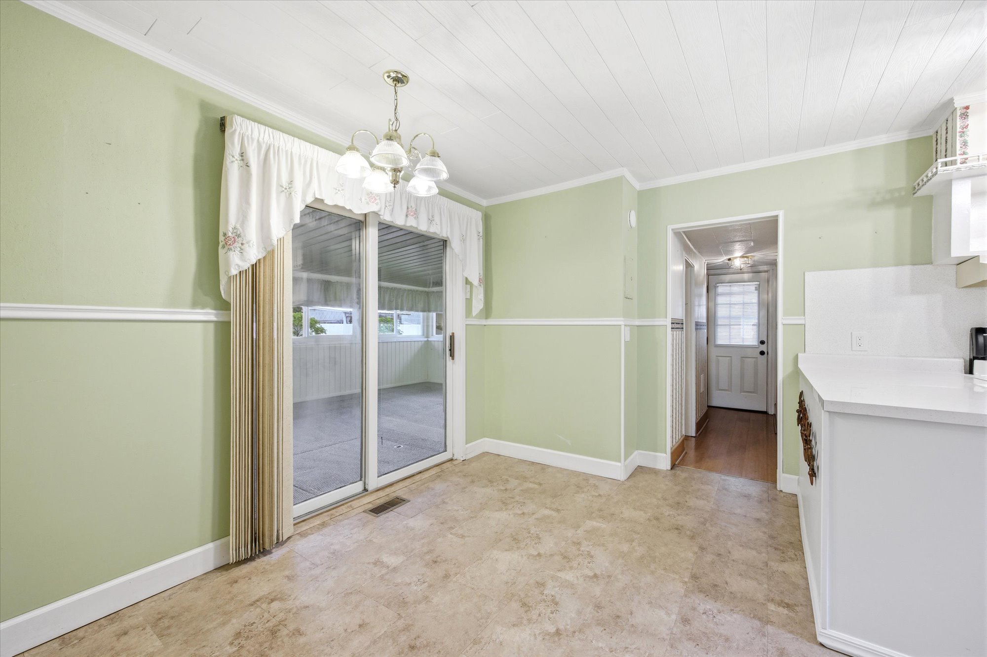 Dining area with light green walls, white trim, and a paneled ceiling