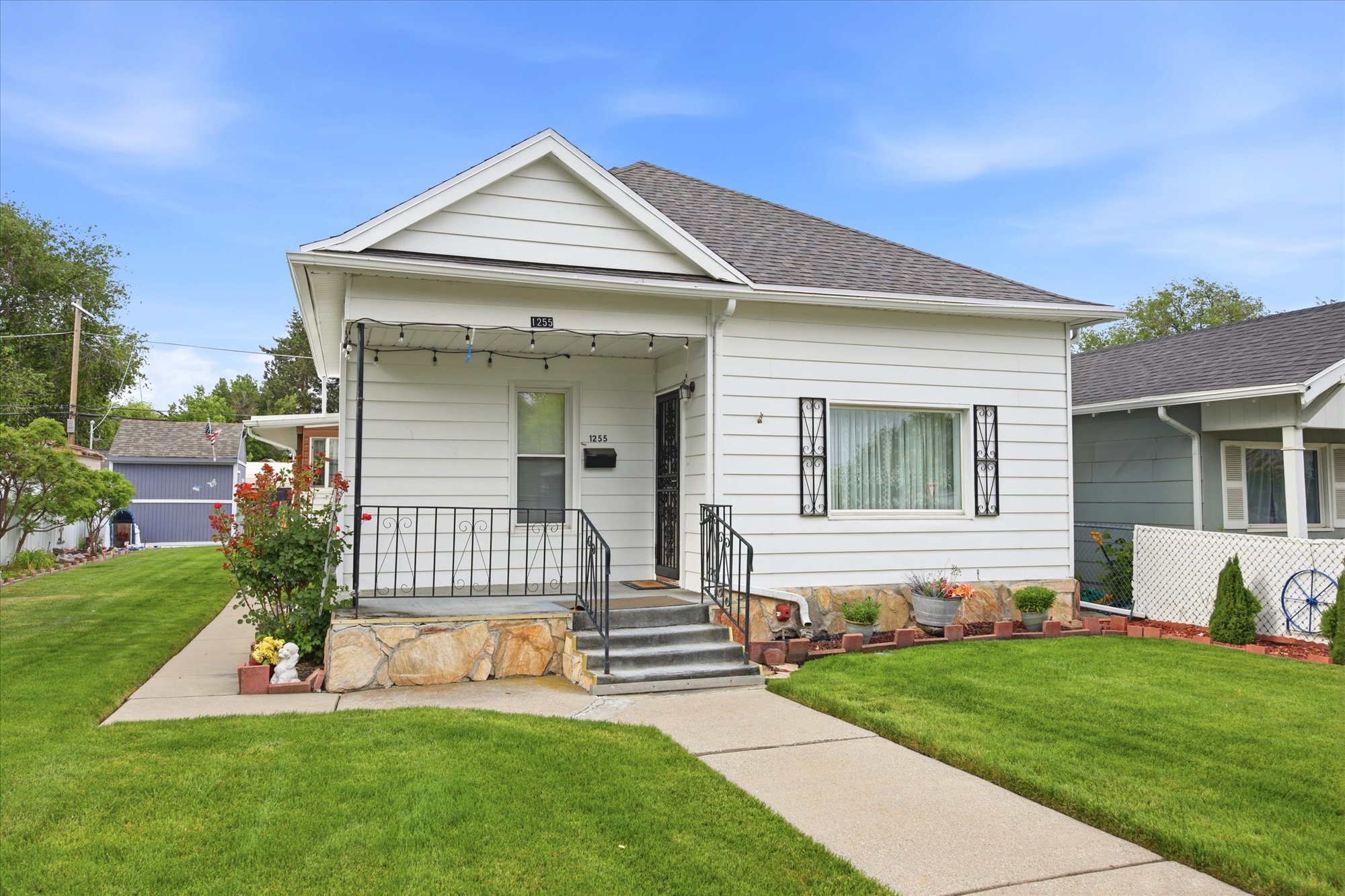 White siding residence featuring a covered front porch with wrought iron railing