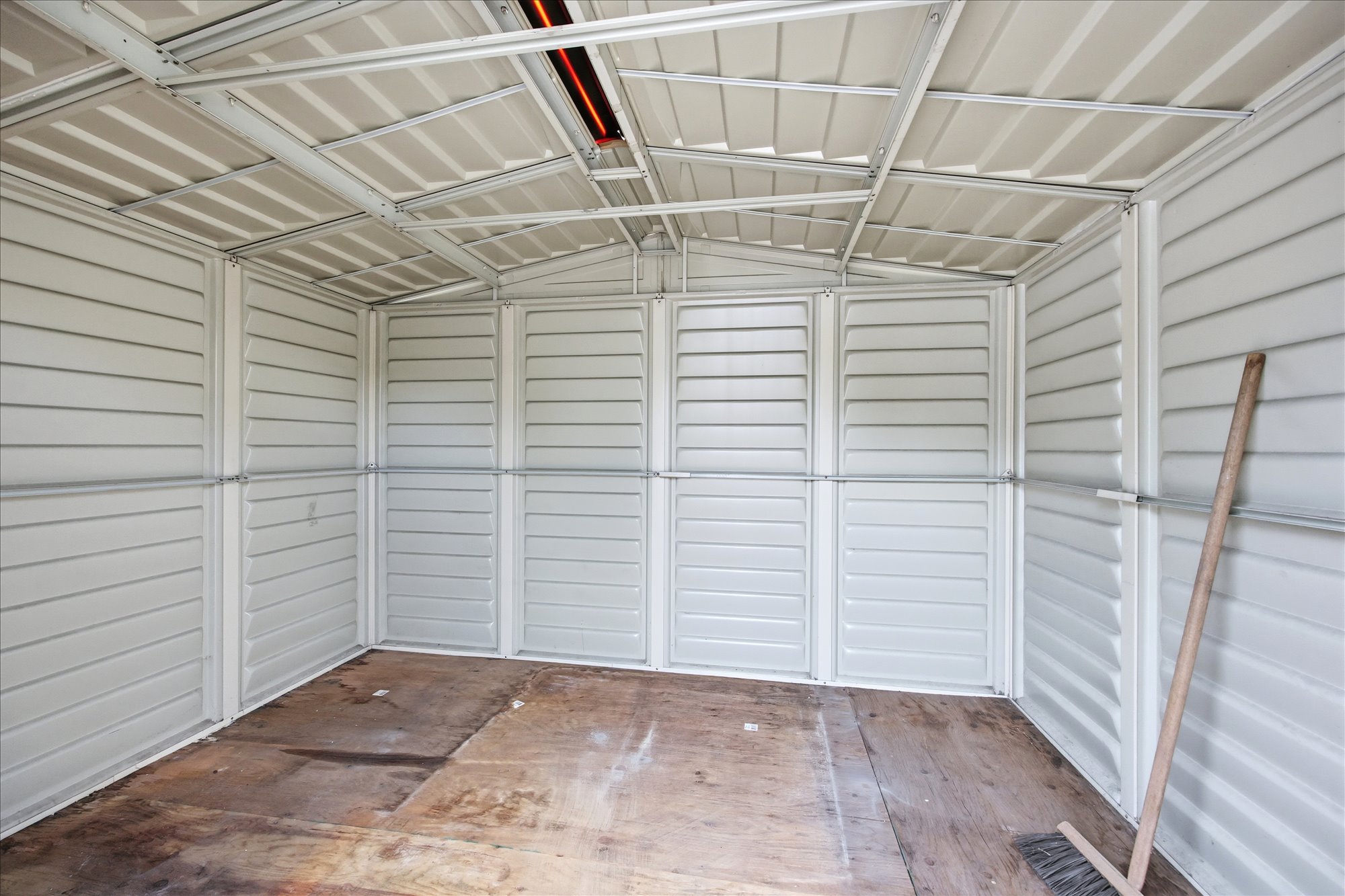 Storage structure featuring corrugated metal walls, a slatted ceiling, and an exposed wood-finish floor