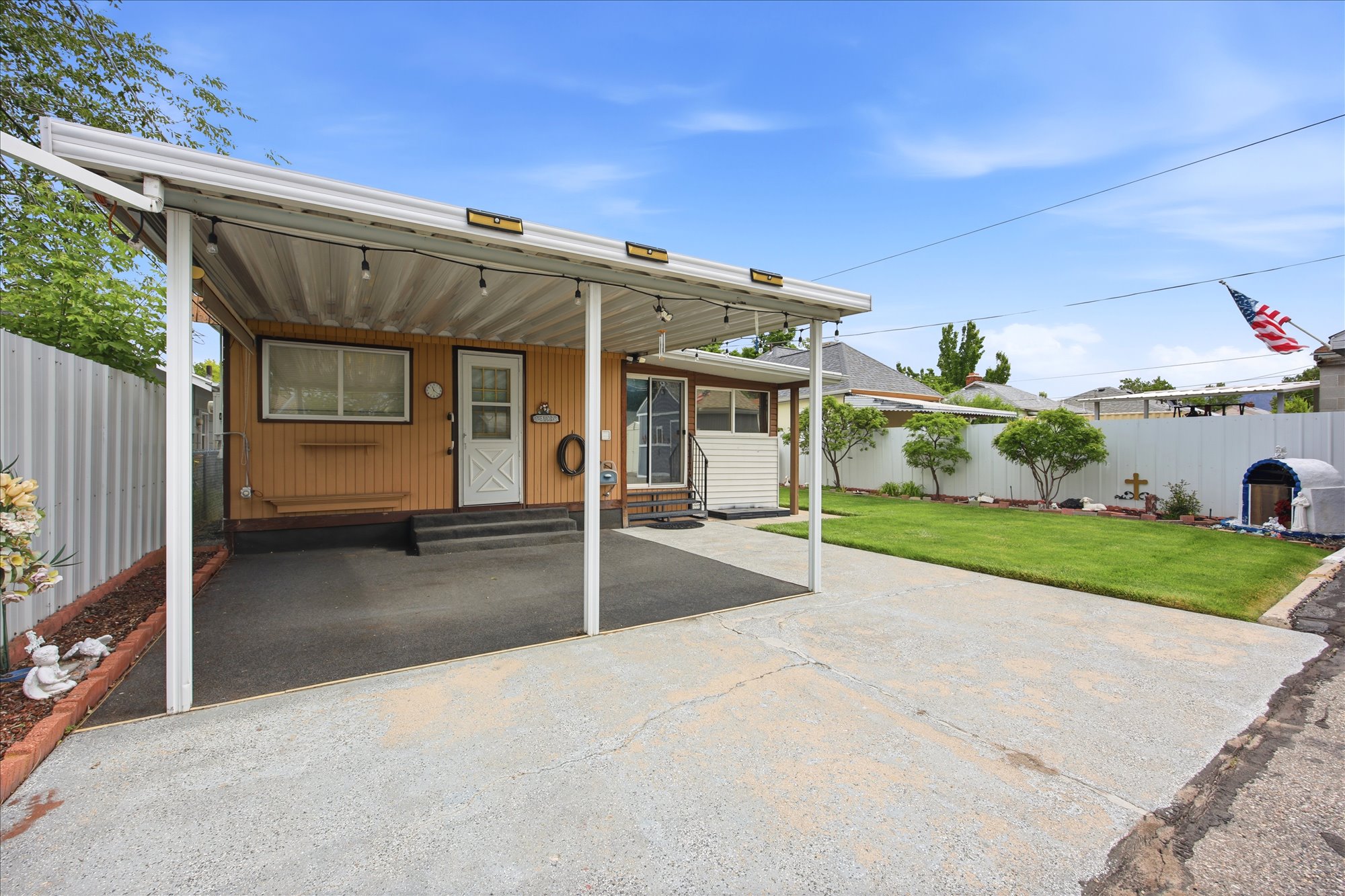 Covered carport with string lighting, providing sheltered parking and entry