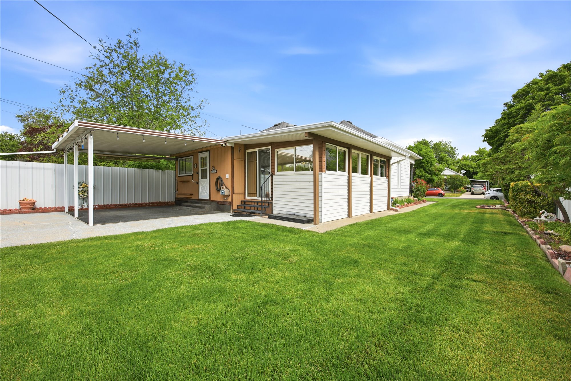 Expansive green lawn with a white privacy fence